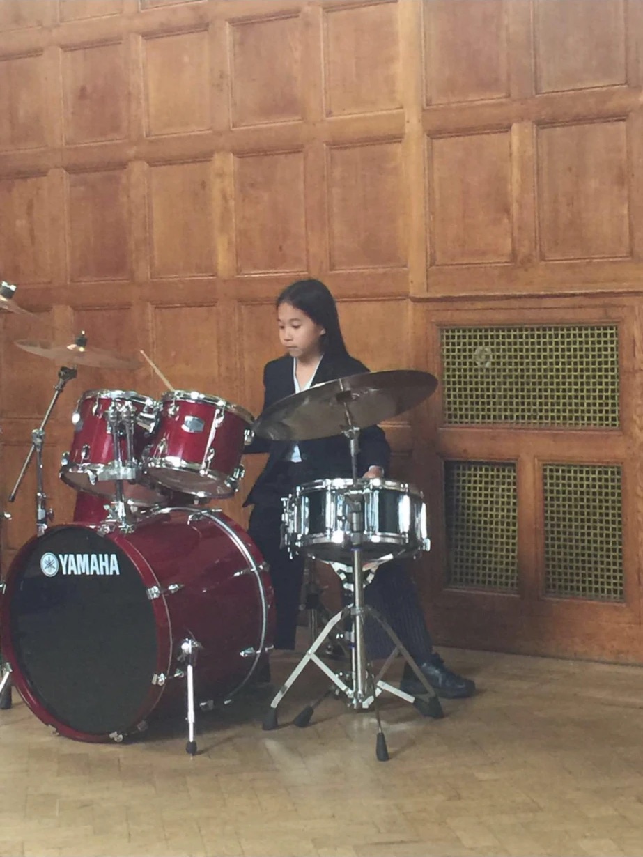 Tyan Lee as a child playing a red drum kit