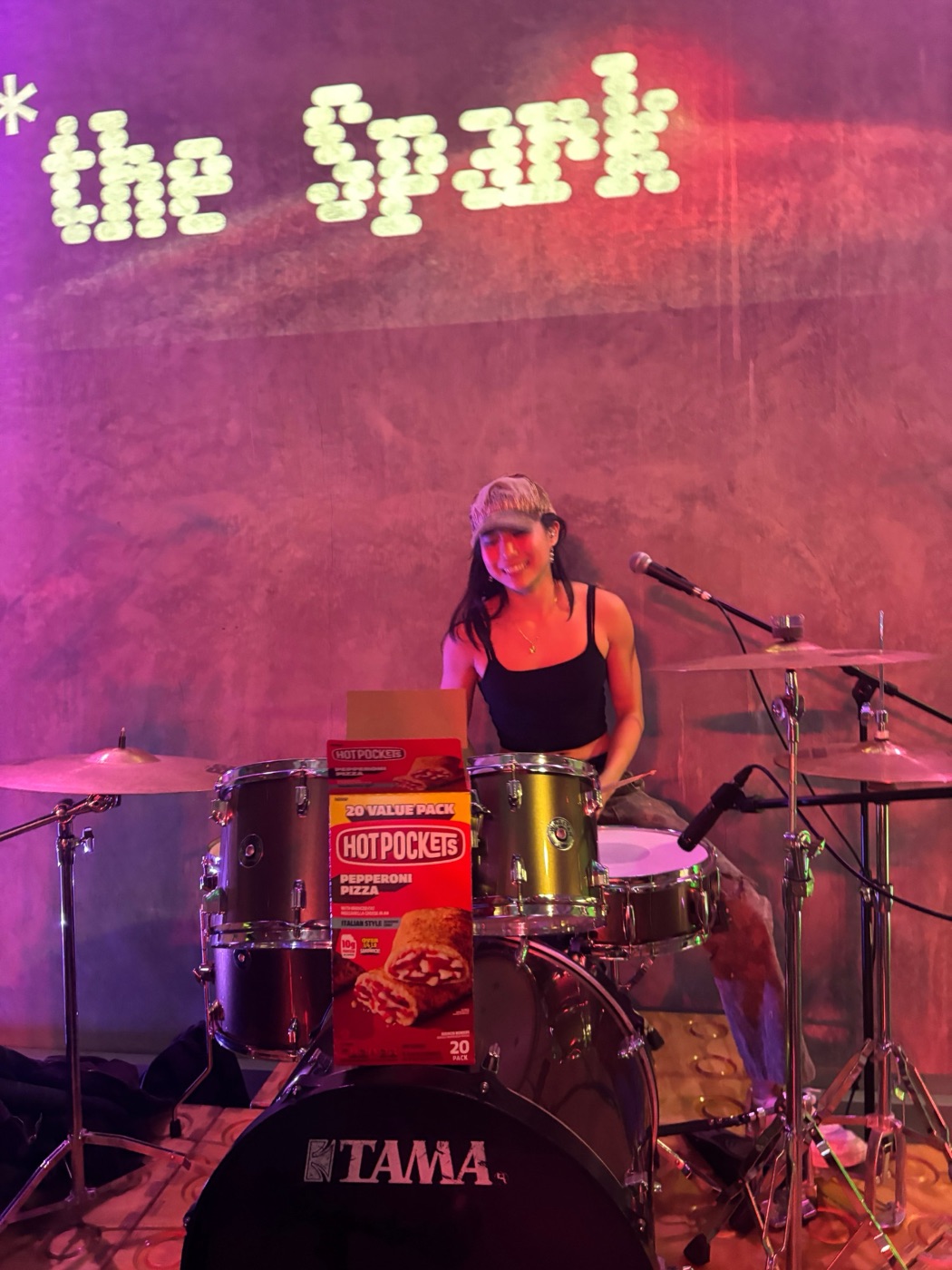 Tyan Lee behind a drum kit with a box of Hot Pockets propped on the bass drum